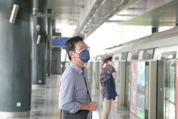 istock Man commuter with face mask on standing on the subway platform waiting to go inside train. Masked transit concept. 1366696061