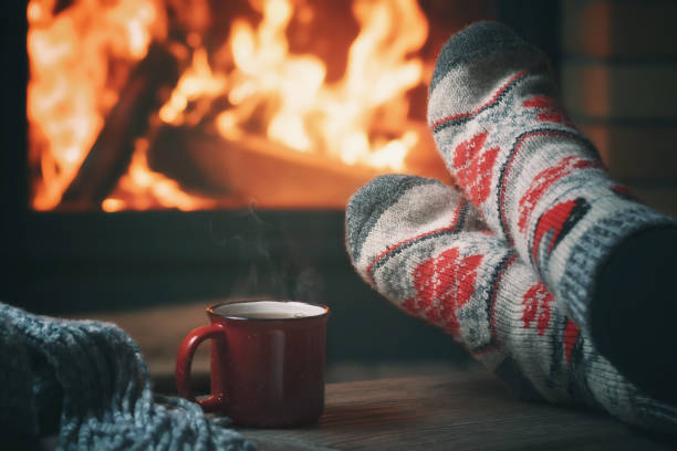 mädchen, das sich an einem winterabend an einem brennenden kamin in einem landhaus ausruht und seine füße wärmt. selektiver fokus - behaglich stock-fotos und bilder