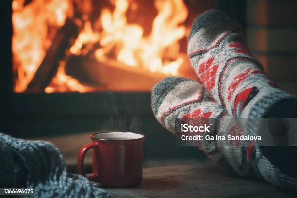 Girl Resting And Warming Her Feet By A Burning Fireplace In A Country House On A Winter Evening Selective Focus Stock Photo - Download Image Now