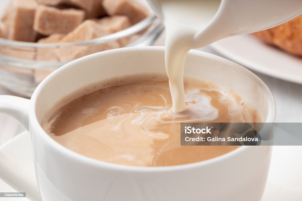 Pouring milk or cream into freshly brewed coffee, close up Pouring milk or cream into freshly brewed coffee, close up. Coffee - Drink Stock Photo