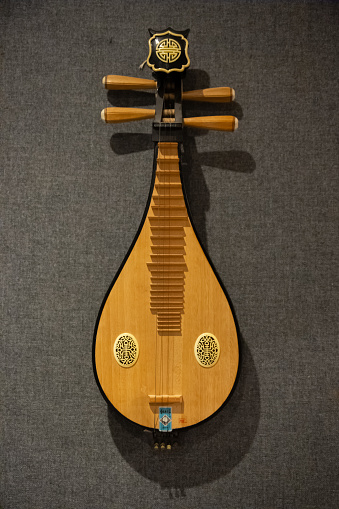 An antique Asian music instrument, pipa, hanged in a wall in a music studio in Canada.