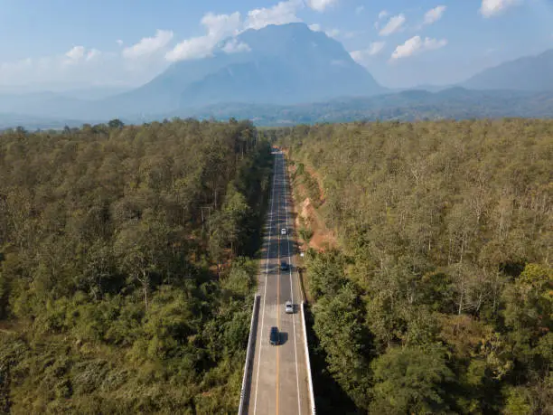 Photo of Aerial view of car driving on the highway road leading to Doi Luang Chiang Dao mountain in Chiang Mai province of Thailand.