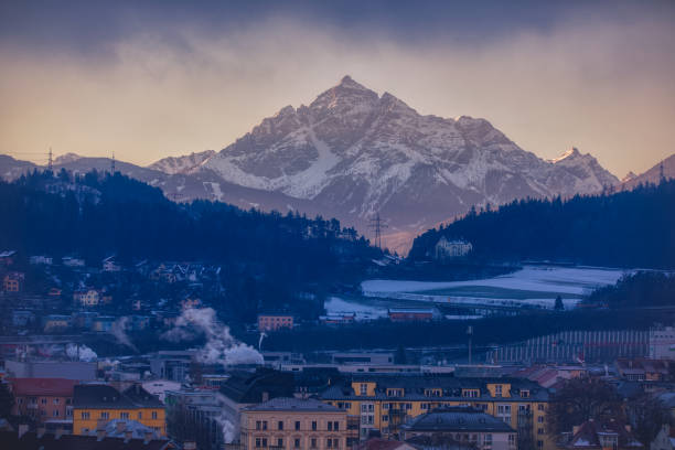 A mountain in the Austrian Alps lit by the early morning sun with Innsbruck, Austria in the foreground.