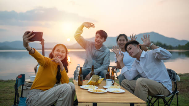 Group of Friends camping together and using Smart phone selfie while vacation stock photo