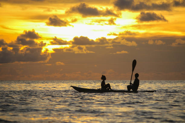 Canoeing in sunset Two kids from Petats Island enjoy the sunset moment on their canoe. This is on the West Coast of Buka in Bougainville, Papua New Guinea. Papua New Guinea stock pictures, royalty-free photos & images