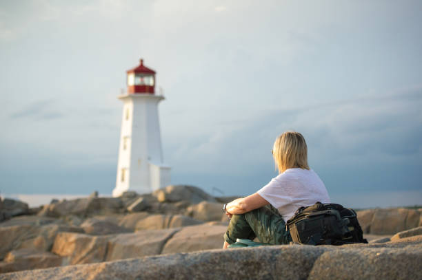 Young woman sitting on Peggy's Cove rock stock photo