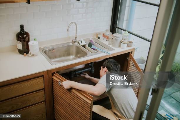 Southeast Asian Repairman Working In The Kitchen Stock Photo - Download Image Now - Leaking, Water, Kitchen Sink