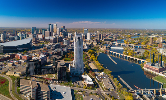 Aerial of Minneapolis during early Autumn with Downtown Minneapolis on the left and the Mississippi River and several bridges on the right.