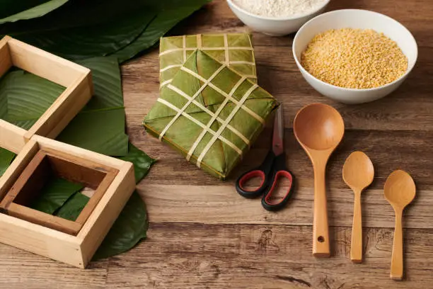 Wrapped sticky rice cakes, with yellow mung beans filling, wooden spoons and forms for cooking