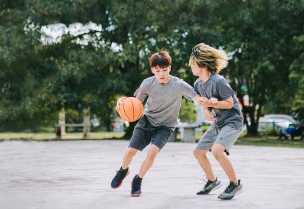 2 geração z asiático adolescente chinês um em um desafio jogando basquete durante o fim de semana de manhã praticando jogo de basquete - basketball child dribbling basketball player - fotografias e filmes do acervo