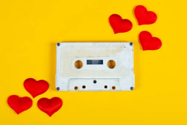 Old Audio Cassette with a Red Hearts on the Yellow Paper Background closeup