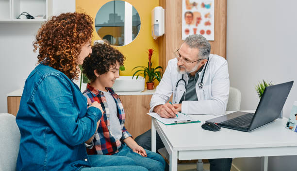 Friendly pediatrician communicate with her child patient at doctor's office while pediatrician consultation. Kid health stock photo