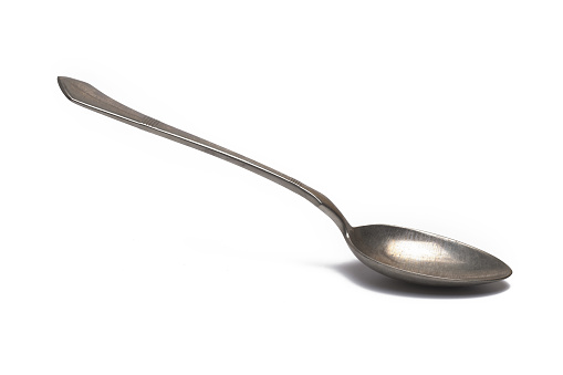 Close up of old retro vintage silver dessert tea spoon on white background
