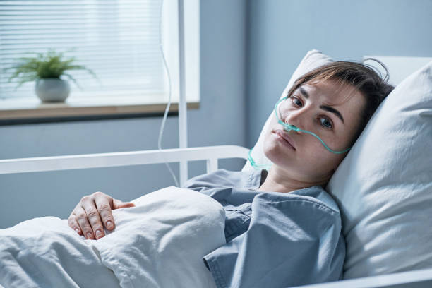 Young woman treating at hospital Portrait of young woman lying on bed with oxygen tube looking at camera while treating at hospital sick woman hospital bed stock pictures, royalty-free photos & images