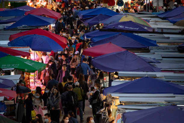 sous la propagation de la variante omicron, les gens vont toujours sur un marché de rue en achetant des ornements du nouvel an chinois et d’autres produits à la tête du prochain nouvel an lunaire chinois 2022 - crowd kowloon peninsula multi colored photos et images de collection