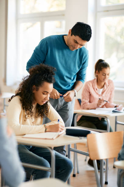 istock High school teacher assisting black female student during a class in the classroom. 1366724816