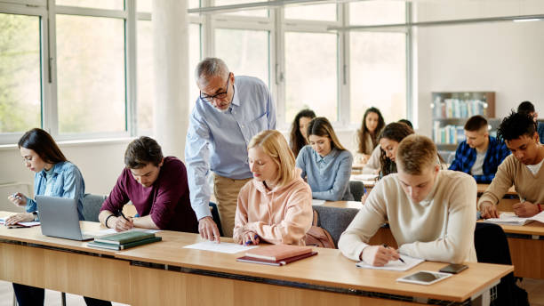 istock Mature professor assisting his student on a class at university classroom. 1366724819