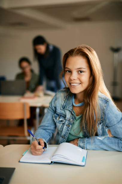 istock Happy high school student writing in notebook during a class and looking at camera. 1366724939