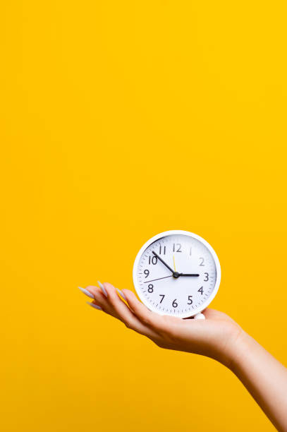 istock hand and white alarm clock on a yellow background with space to place text in good work 1366726088