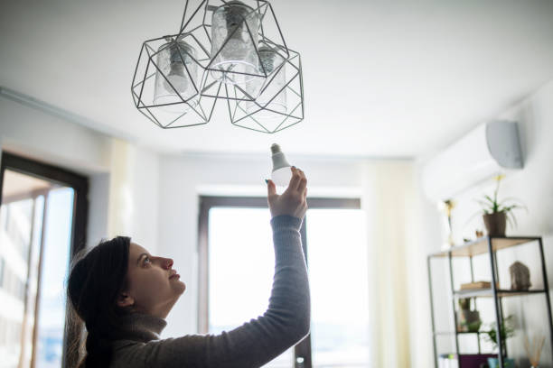 istock Woman changing energy efficient light bulb in living room. 1366730836