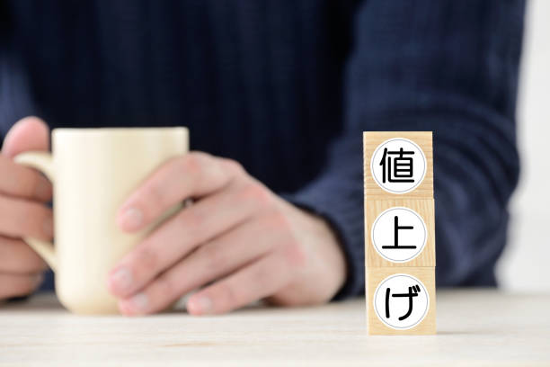 Human with coffee cup and wooden blocks with rising price word in Japanese word Human with coffee cup and wooden blocks with rising price word in Japanese word consumer confidence photos stock pictures, royalty-free photos & images