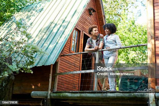 Couple Standing Outside Cabin At Start Of Weekend Getaway Stock Photo - Download Image Now