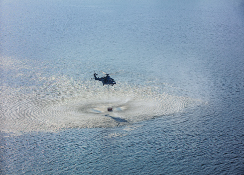 Helicopters fetch water at sea rolled up swirling waves.