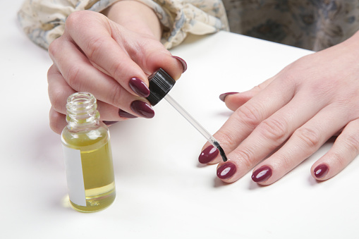 Mujer aplicando aceite de cutícula en las uñas. Cuidado de la piel de las manos en casa con aceite hidratante. Belleza, estilo, maquillaje, moda, concepto de estilo de vida. photo