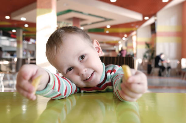 istock The kid is bored in a cafe, plays fries 1366737123