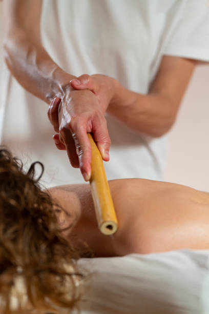 istock Woman masseuse performs a massage with a bamboo cane to a woman's neck 1366738025