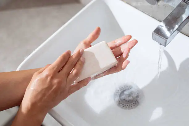 Close up shot of an anonymous young Caucasian woman washing her hands with soap and water in a bathroom early in the morning.