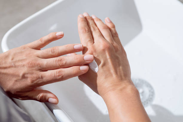 anonimo giovane donna caucasica che applica una crema per le mani in bagno - contemporary domestic room sparse indoors foto e immagini stock