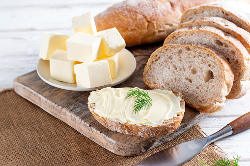 Toasted Garlic bread with herbs and butter on wooden cutting board. Wooden background. Top view.