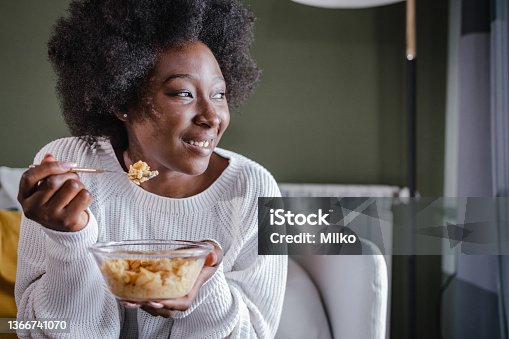 istock Happy woman eating cereals for breakfast at home 1366741070
