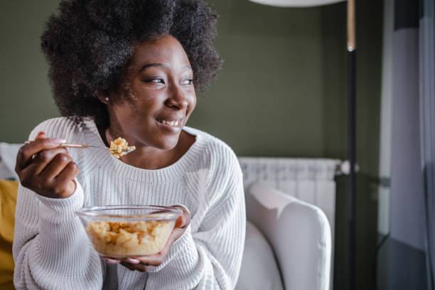 Happy woman eating cereals for breakfast at home stock photo