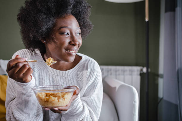 happy woman eating cereals for breakfast at home - eating women breakfast cereal imagens e fotografias de stock