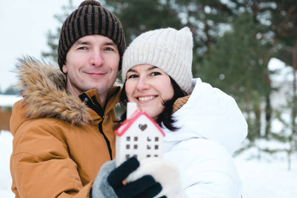 Man and woman in love outdoor date in winter with symbol of home and love. Valentine's Day, happy couple, love story. Love nest, mortgage, relocation, purchase, real estate, housing for young family stock photo