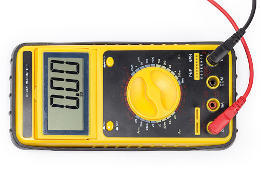 Front panel of the modern portable universal digital multimeter in protective rubber cover with connected test leads on a white background, top view