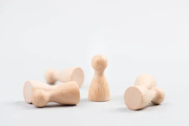 Photo of Group of wooden figures, one leader is standing, others have fallen, outstanding leadership, successful strategy, business concept, be the winner