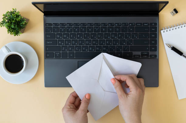 istock Women's hands open a letter. Workspace, top view: laptop, coffee cup, notepad, female hands, top view 1366743934