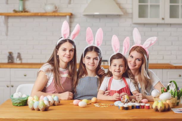 istock Happy easter. Mother and daughters with rabbit ears decorate Easter eggs at a table in kitchen. 1366744802