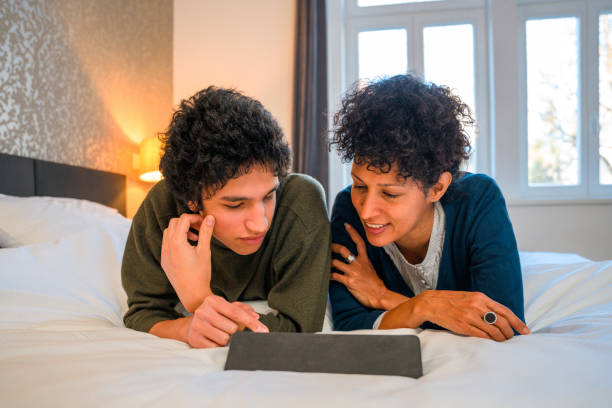 istock Hispanic Mother And Son Lying in Bed and Using Digital Tablet 1366746059