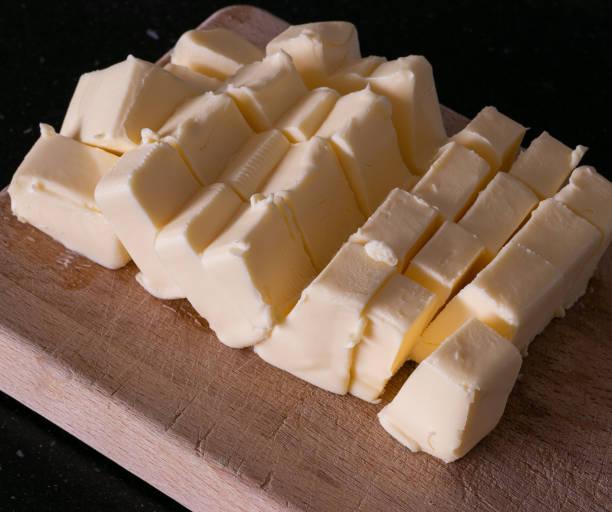 Butter sliced in cubes for baking Butter sliced in cubes for baking on a wooden board margarine stock pictures, royalty-free photos & images