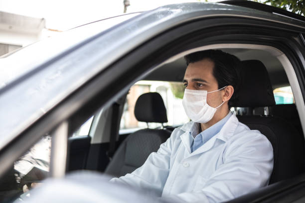 istock Latin doctor driving his car - wearing protective face mask 1366748559