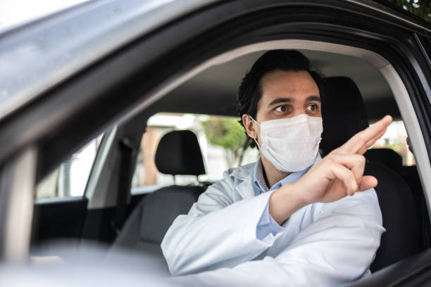 istock Latin doctor greeting someone from his car - wearing protective face mask 1366748563