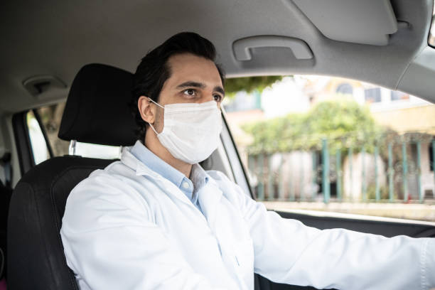 istock Latin doctor driving his car - wearing protective face mask 1366748604