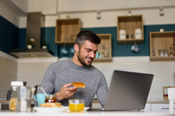 istock Young man making a video call on his laptop during breakfast 1366749933