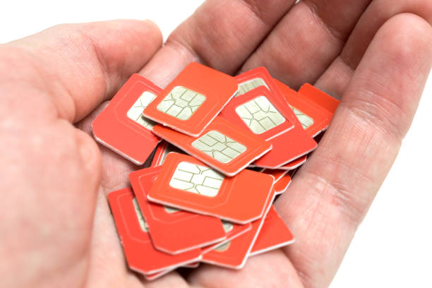 muitos cartões sim de telefone vermelho estão na palma da mão. cartões com chips de comunicação móvel na mão é um close-up. conceito de telecomunicação - prepaid card - fotografias e filmes do acervo
