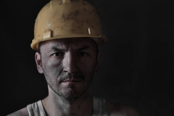 Portrait miner in helmet and undershirt with dirty face