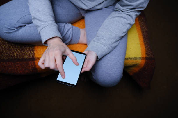 istock Unrecognizable mature woman is sitting on sofa and interacting with smart phone 1366754002